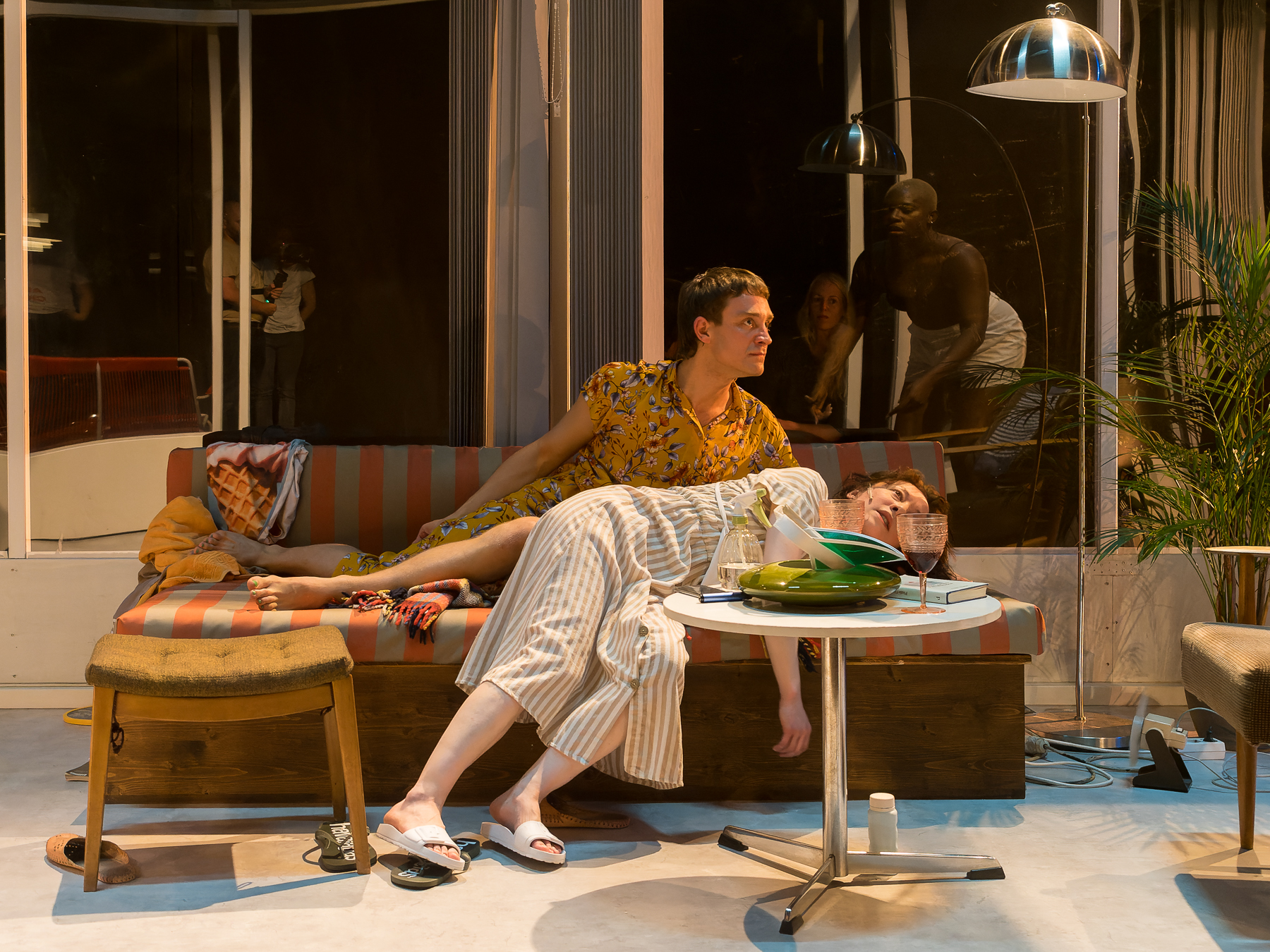 two actors on stage lounging on a sofa